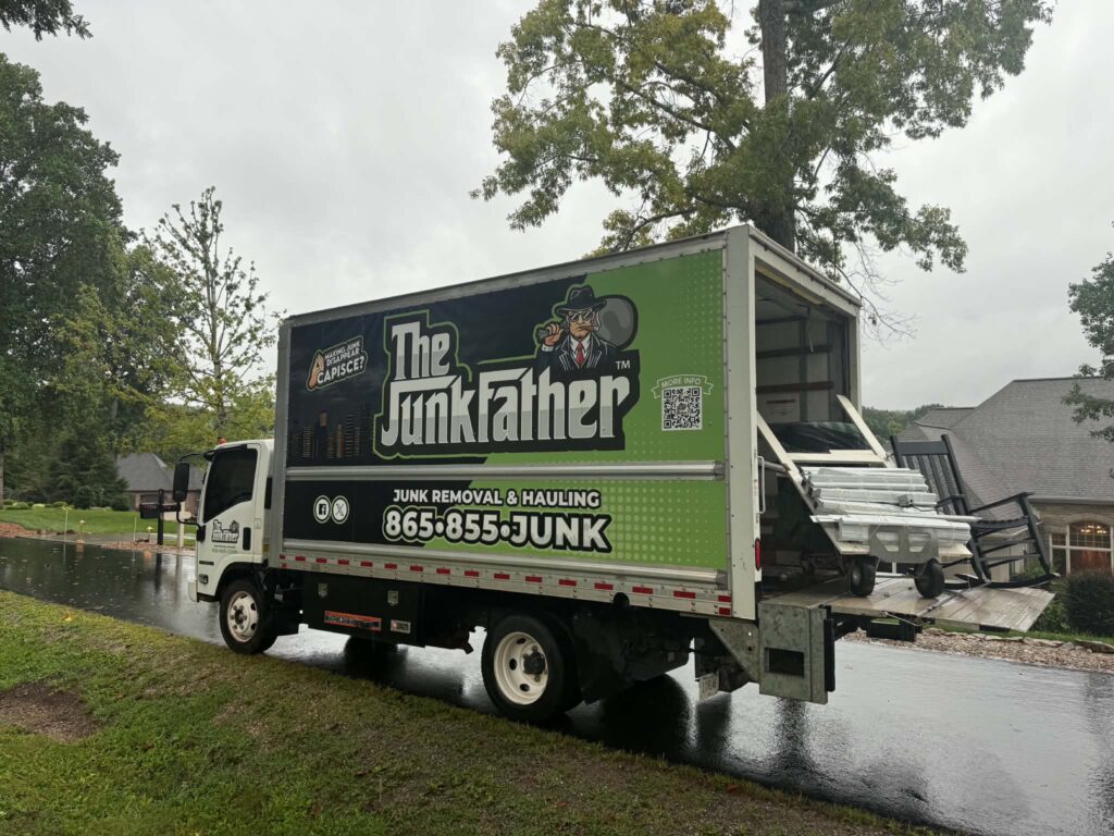 The JunkFather truck with its loading ramp extended during a rainy Tellico Village pickup.