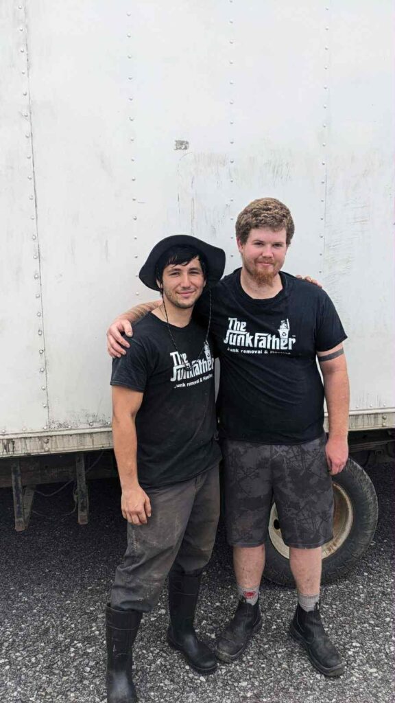 Two members of The JunkFather crew standing in front of an early white box truck.