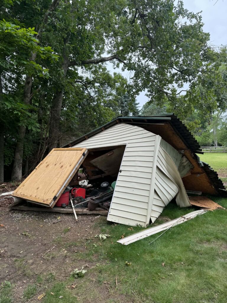 Windstorm-damaged shed with collapsed sections before our removal