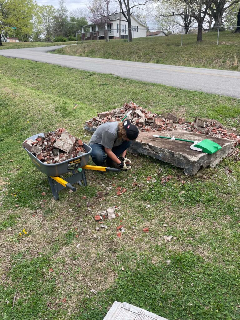 Masonry debris being gathered beside a wheelbarrow during removal