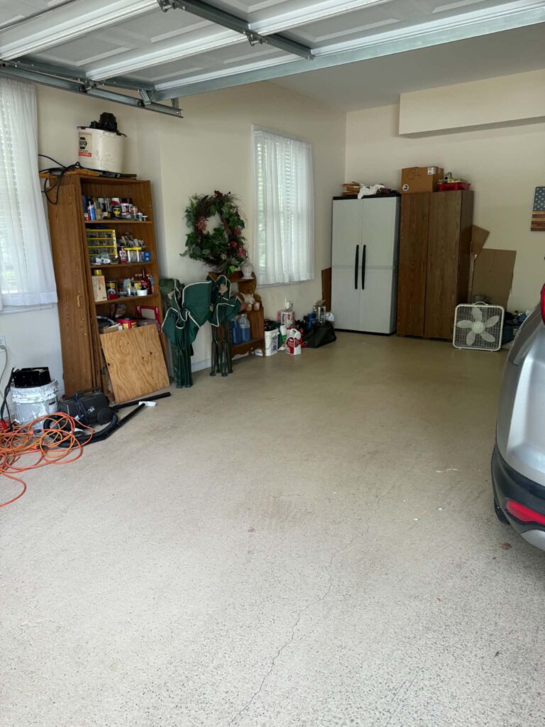 Garage floor after the boxes and loose items were removed, with storage cabinets and wall-side belongings still in place