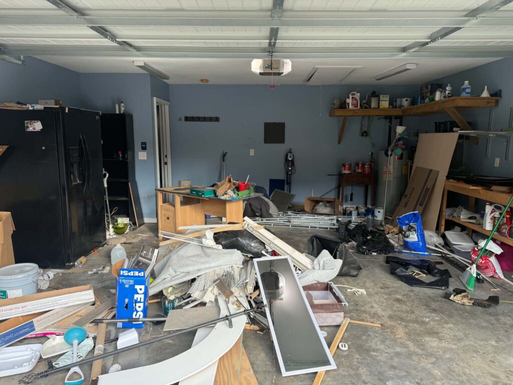 Debris and unwanted household items on the floor of a Tellico Village garage before removal.