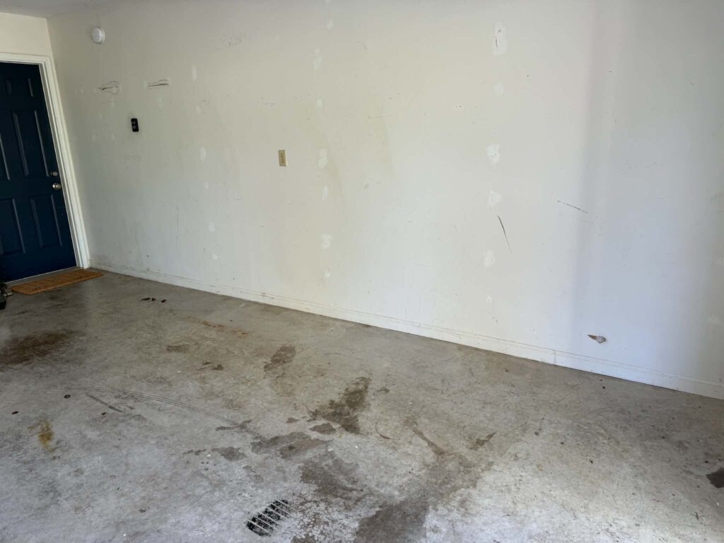 Cleared concrete garage floor beside a dark blue interior door in Oak Ridge.