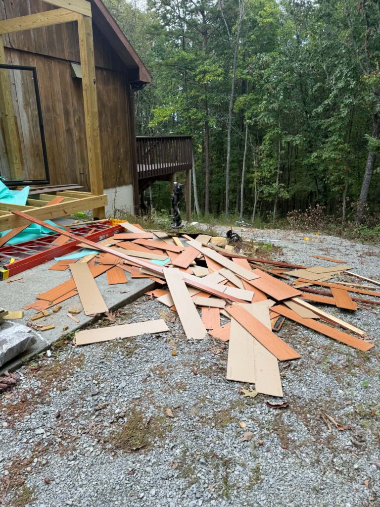 Pile of removed wooden boards beside a deck under renovation.