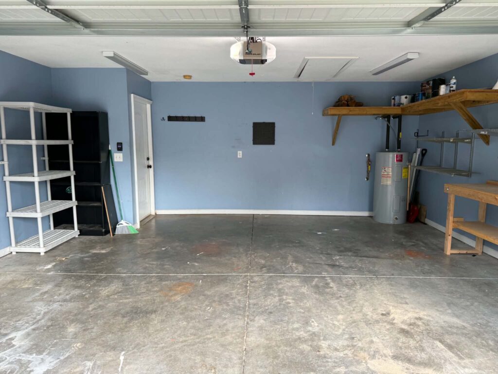 Tellico Village garage after debris removal, with open concrete floor space and remaining shelves and equipment.