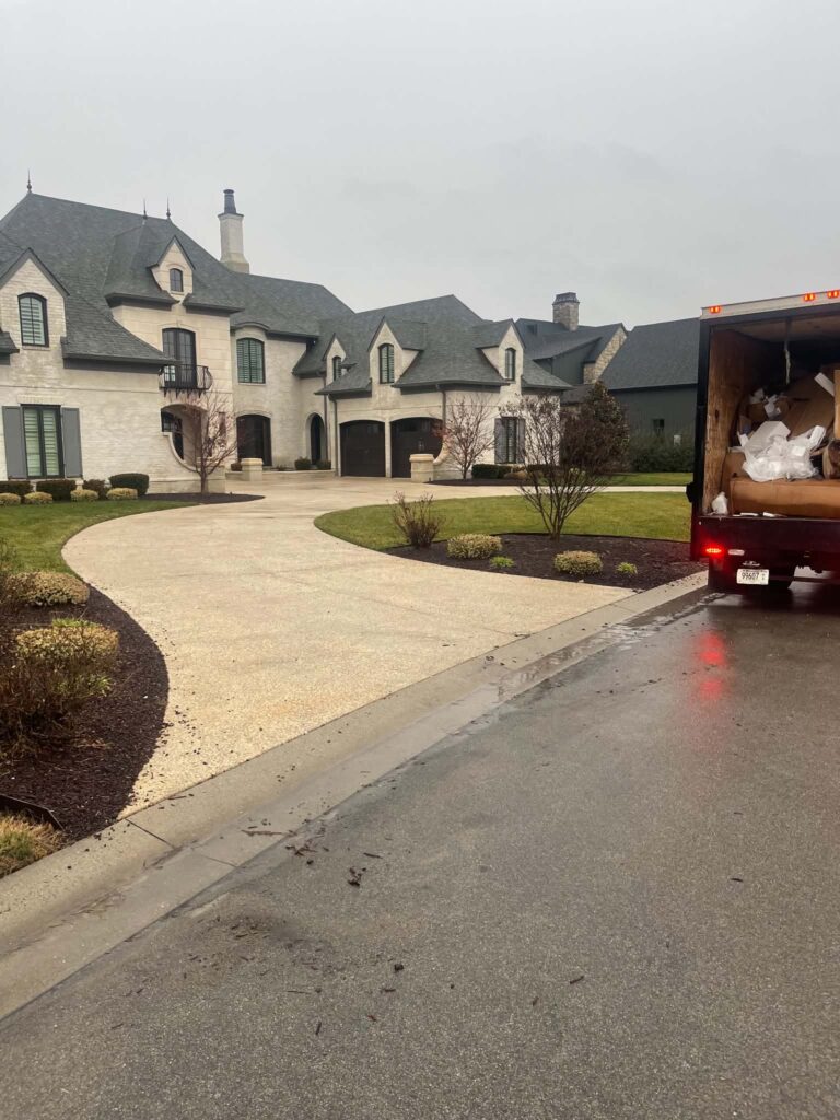 Loaded box truck beside the cleared pickup area at a home after cardboard removal