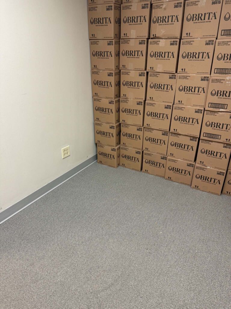 Office storage area after the pallets were removed, with stacked delivery boxes remaining.