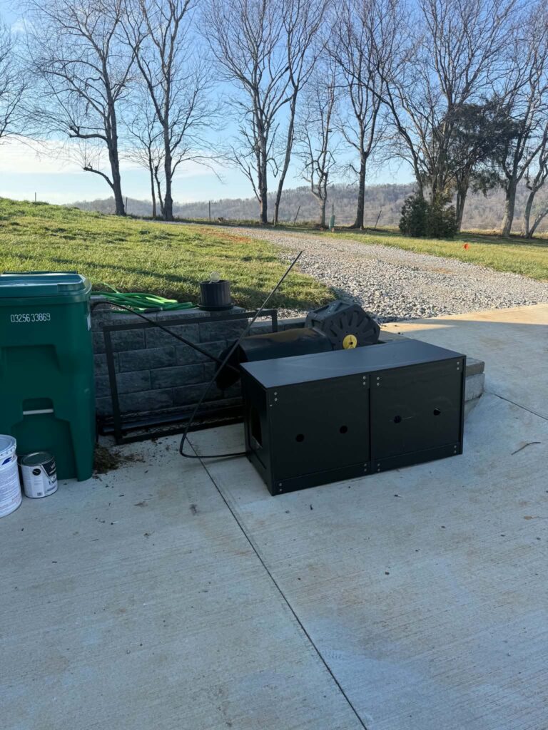 Bulky outdoor items on a concrete area beside a retaining wall and bins before pickup.