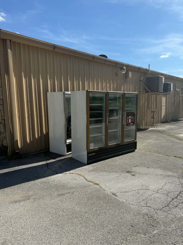 Large commercial refrigeration units beside a corrugated-metal building before pickup.
