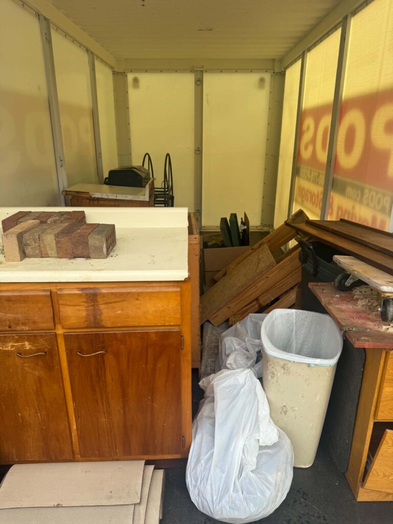Furniture, bags and other unsold estate sale items inside a storage pod before pickup