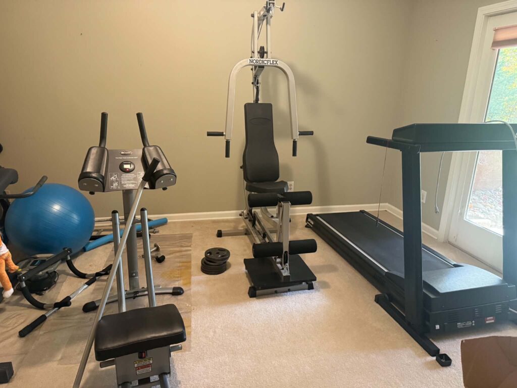 Treadmill, weight-training equipment, and workout accessories in a room before a Maryville junk removal job.