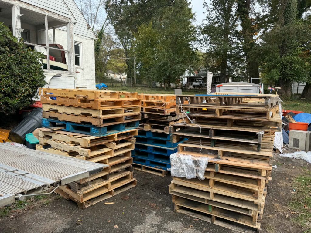 Multiple stacks of wooden pallets outdoors before a bulk pallet pickup.