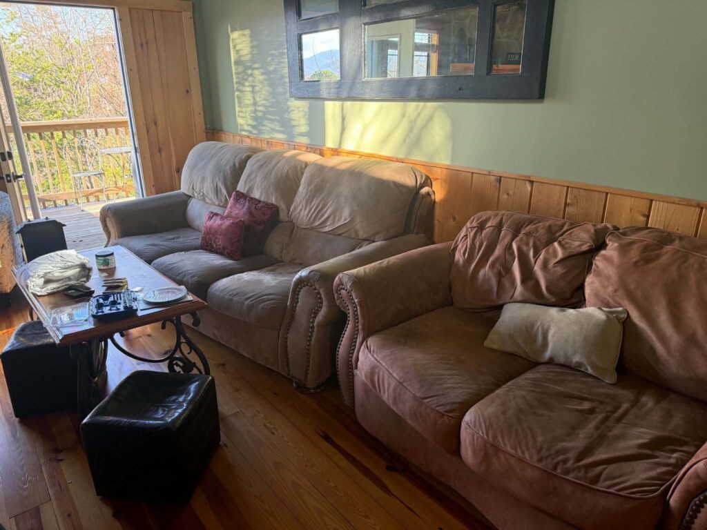 Sofas and a coffee table in a Sevierville cabin rental living room with wood flooring and green walls before furniture removal