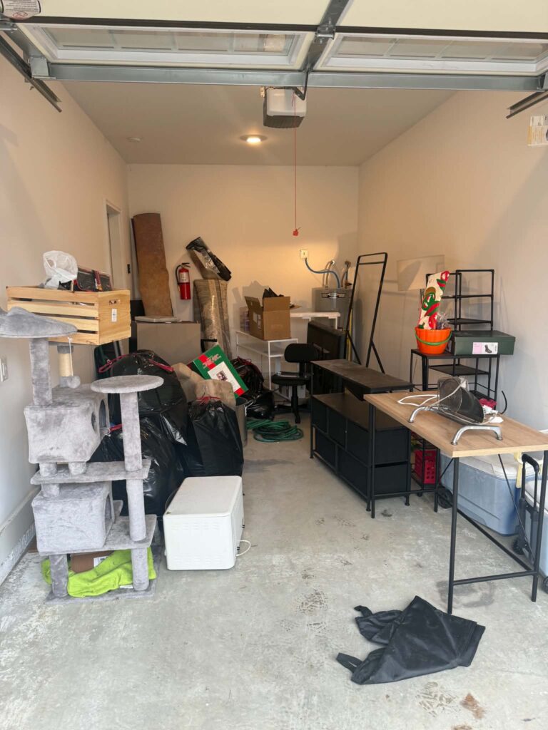 Cat tree, black bags, shelving, and other belongings in an Oak Ridge garage before pickup.