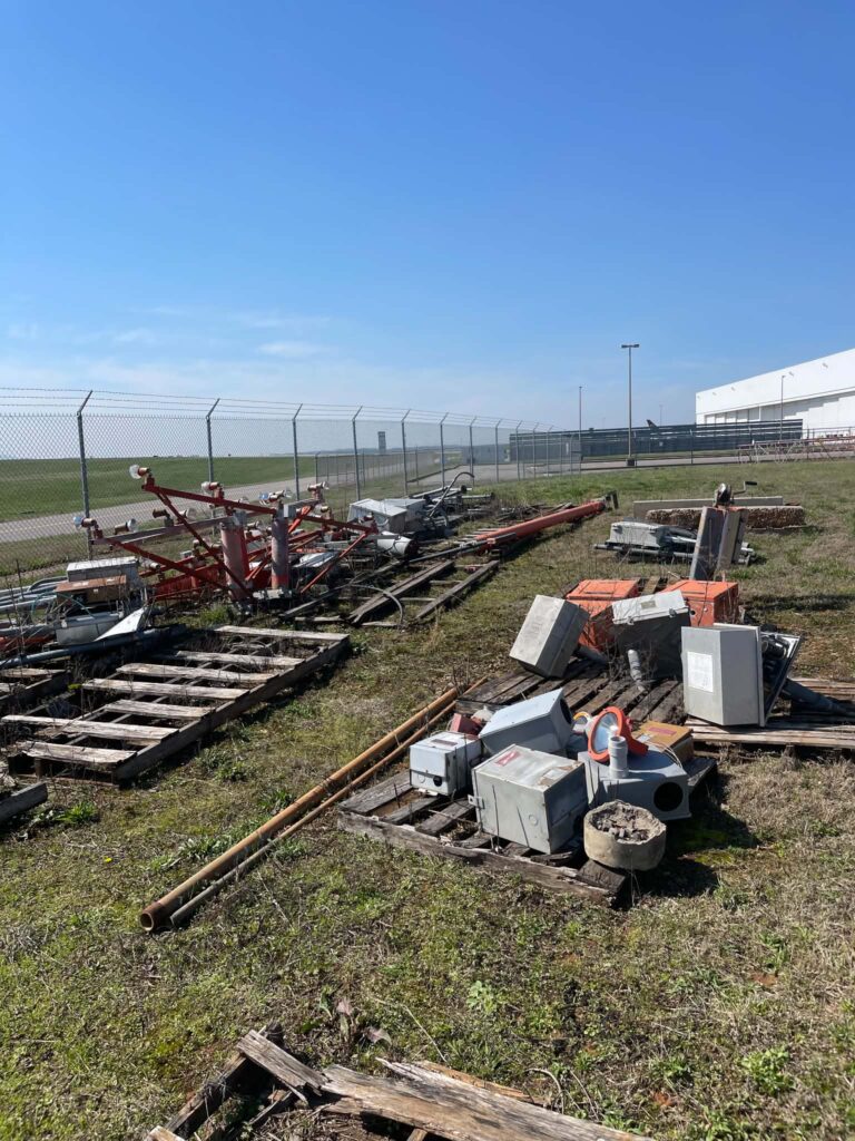 Retired lighting equipment, metal pieces, and other materials gathered on pallets for removal.