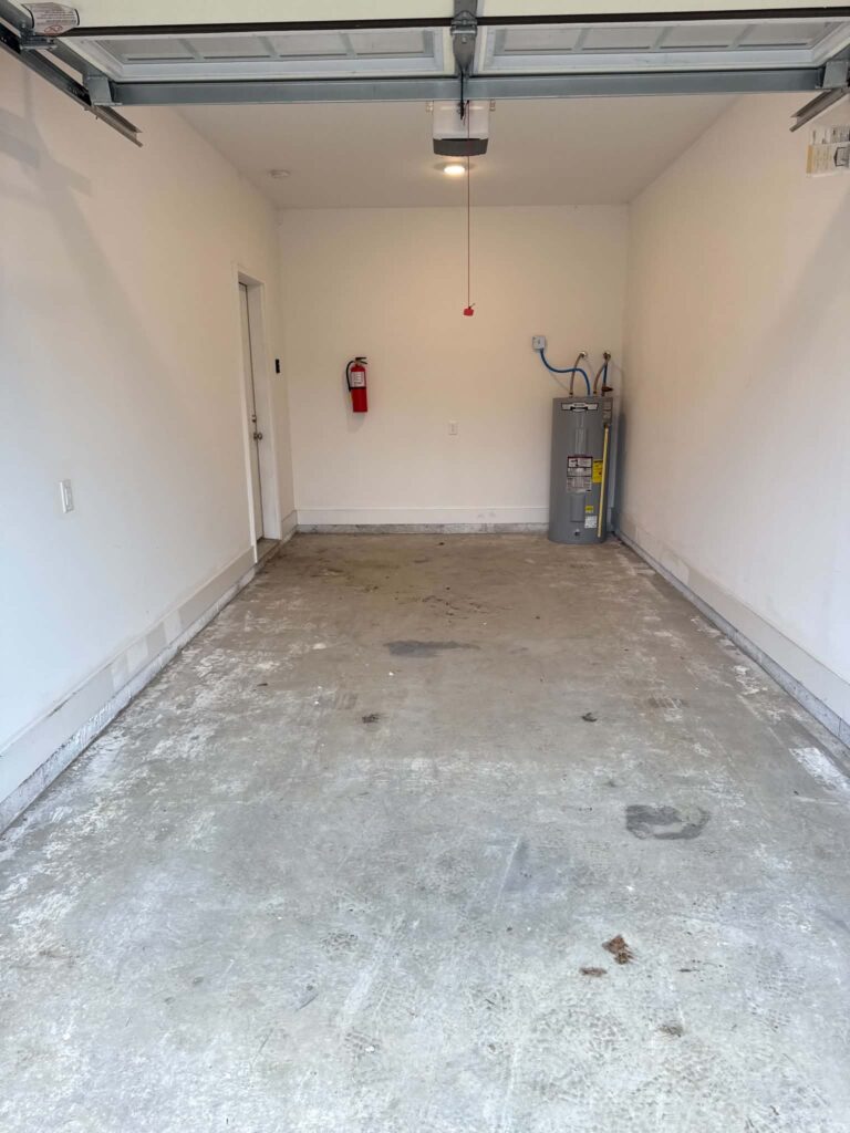 Cleared Oak Ridge garage with a concrete floor, wall-mounted fire extinguisher, and water heater remaining.