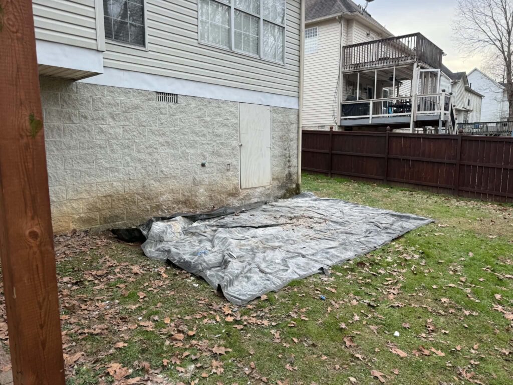 Tarp on the ground beside a house after the remodeling-debris pile was removed.