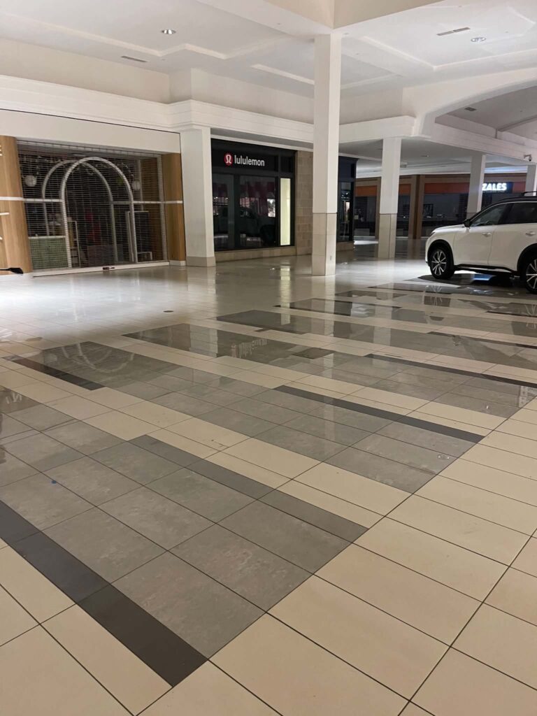 Tiled mall concourse with surrounding storefronts visible during the kiosk-removal project.