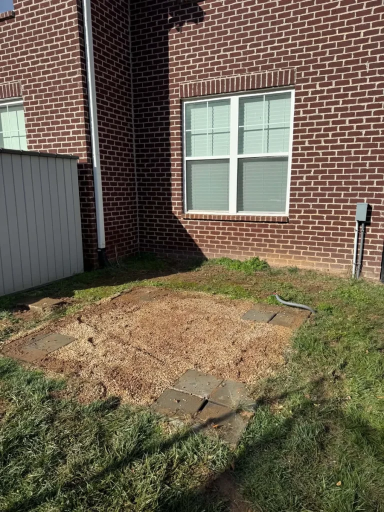 Exposed ground beside the same brick house after hot tub removal
